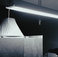 a man is sitting under a lamp in a dark room